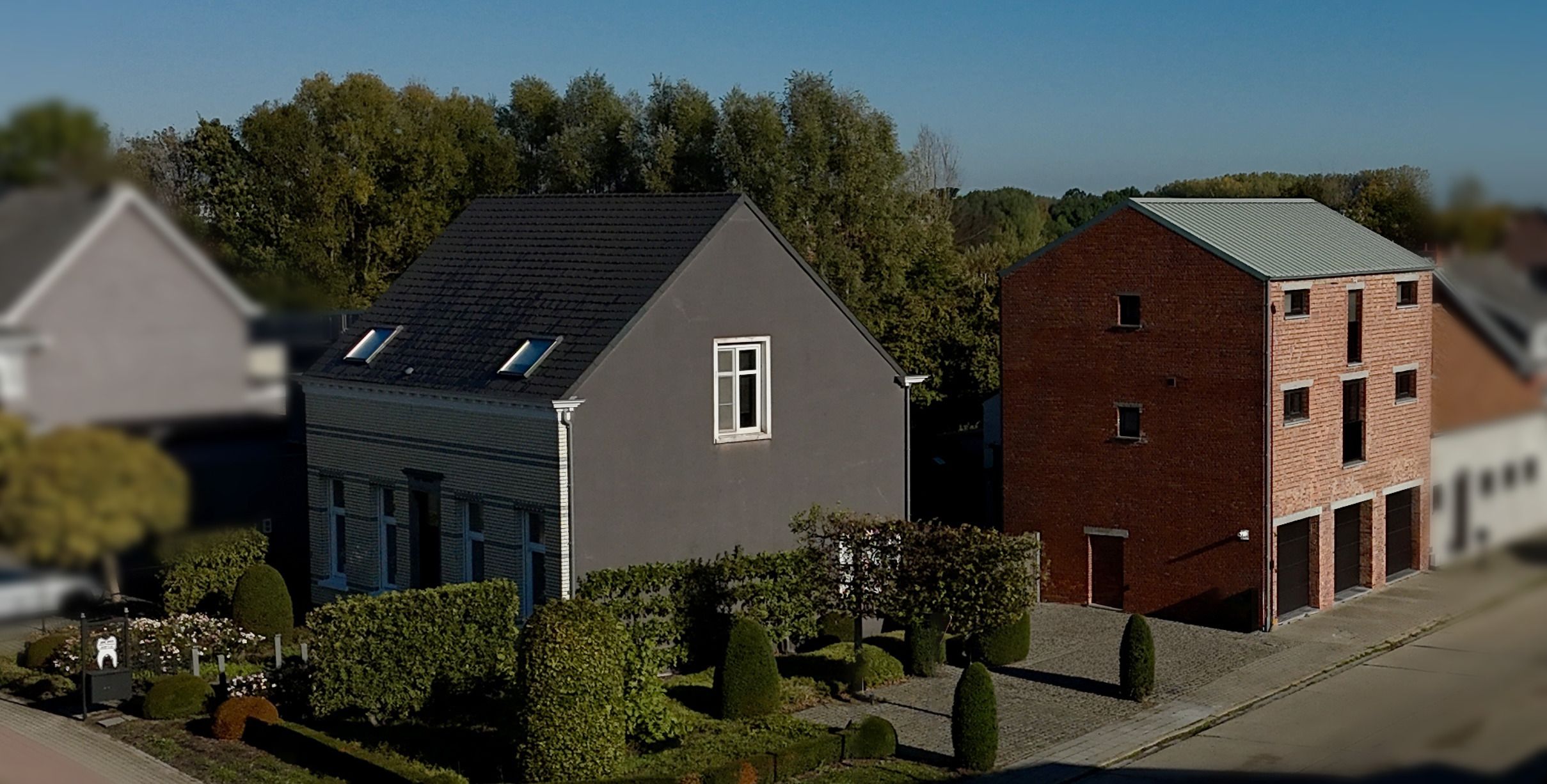 Aerial view of the Retzius premises in Lier: a light grey house with a dark roof beside a brick building with a green roof.